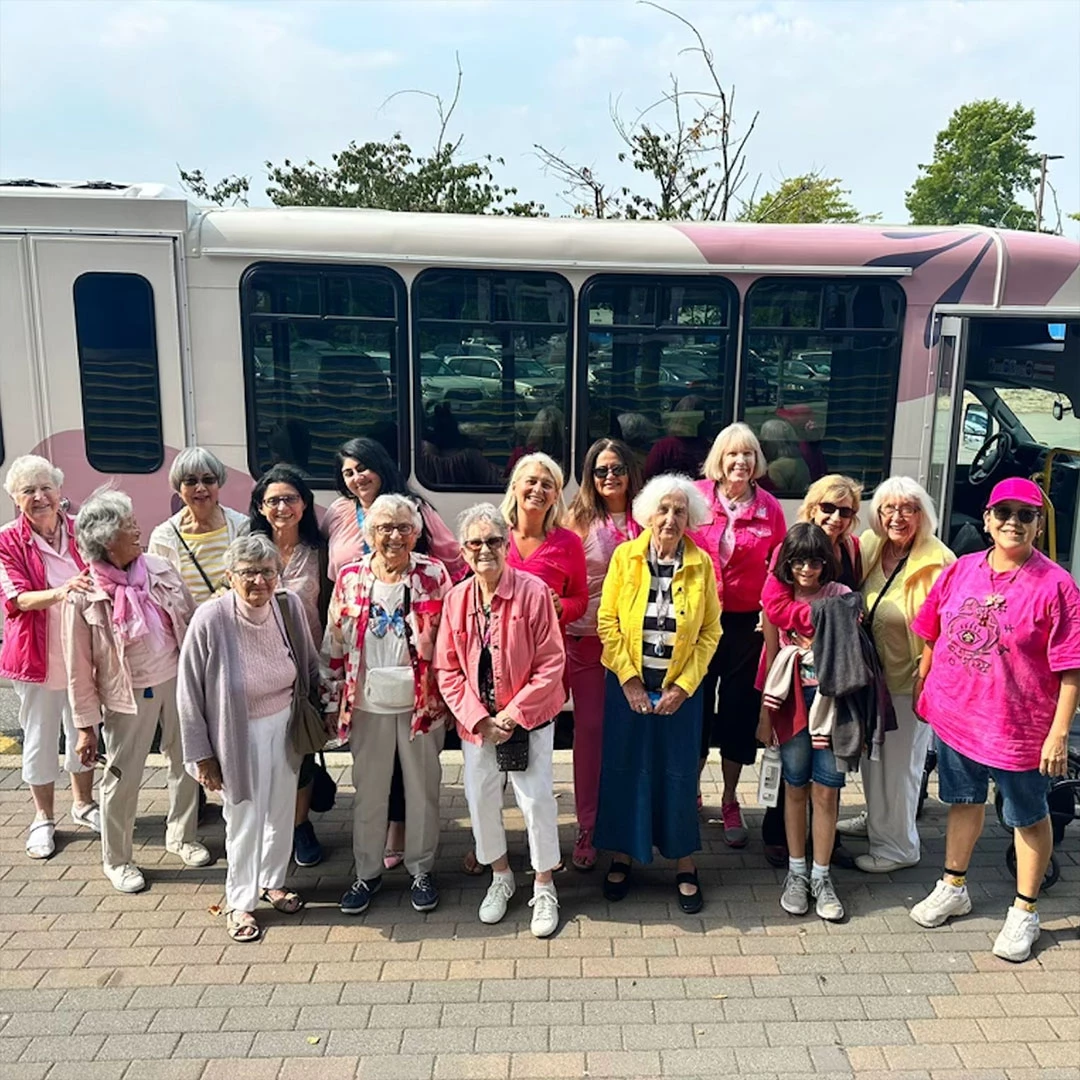 Seniors dressed up in pink for the Barbie movie in front of the Wisteria Place bus