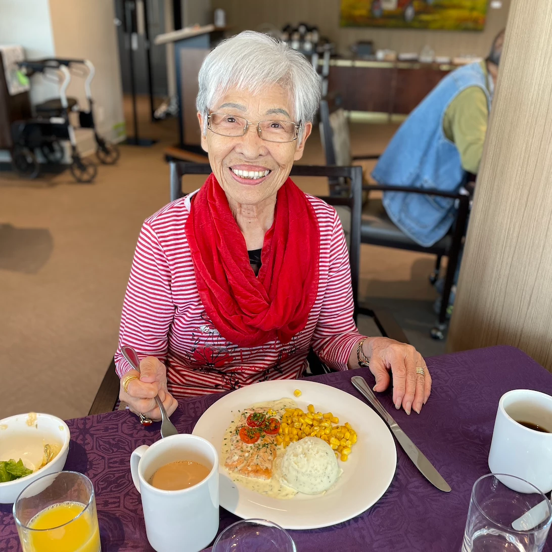 Senior smiling with a delicious looking meal in front of her